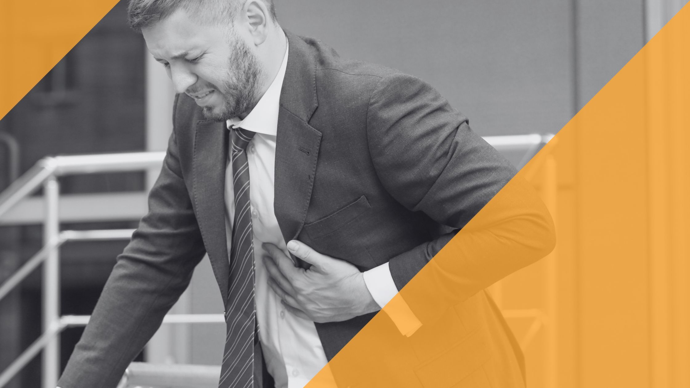 Ein Mann im Business-Outfit fasst sich mit schmerzverzerrtem Gesicht an die Brust